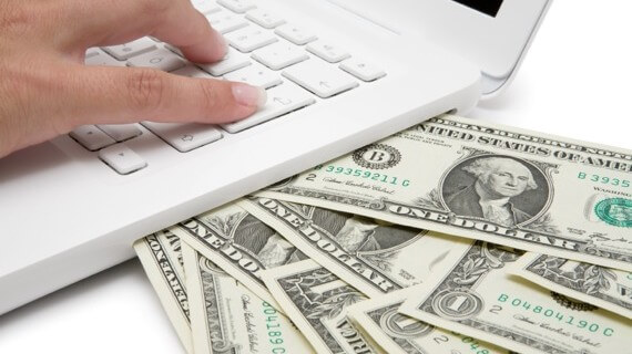Some dollar bills under a laptop, best freelance websites for beginners