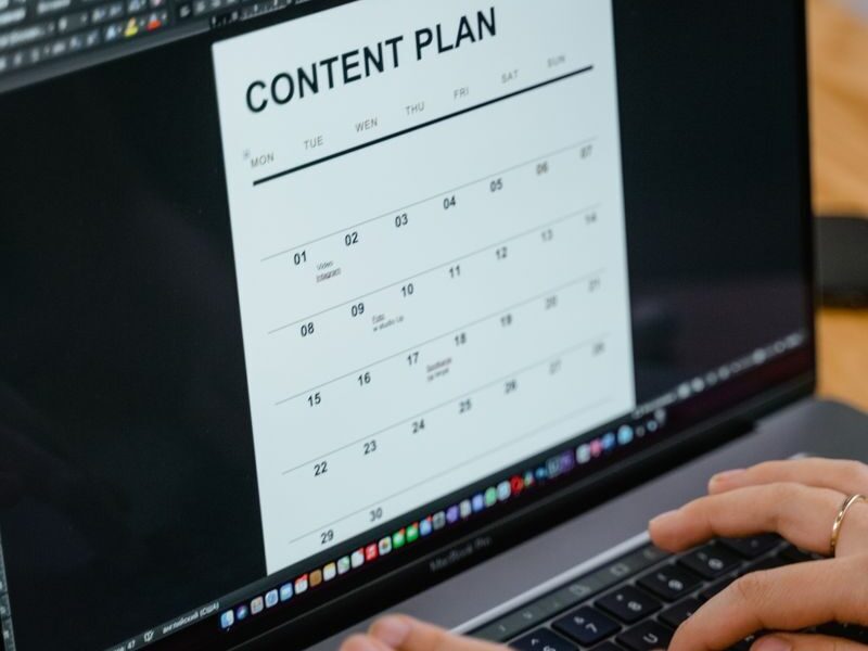 Close-up of hands typing on a laptop displaying a content plan document, ideal for business or marketing content.