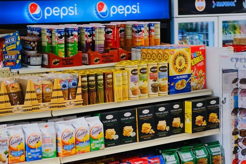 A vibrant display of snacks and beverages on shelves in a store, showcasing variety and abundance.
